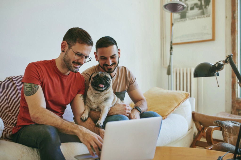 This image of two men holding a dog and a computer represents how easy it is to book an appointment with our kennel software. 